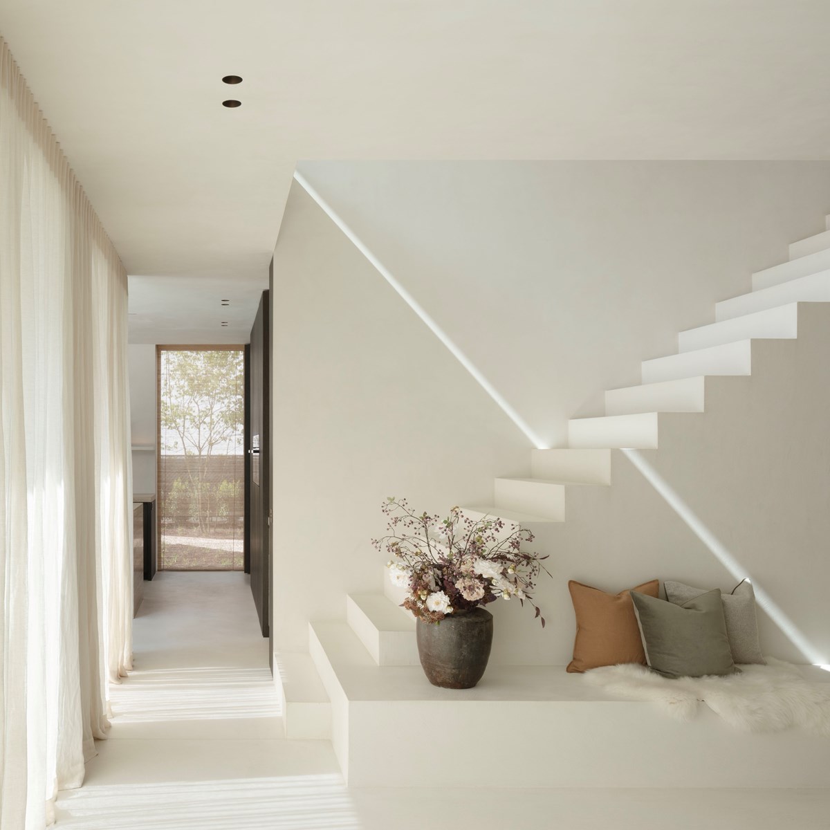 Minimalist light interior with open stairs and recessed round downlighter